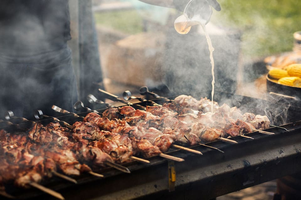 delicious pork skewers grilling on open grill at summer barbecue